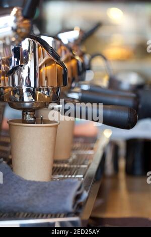 moderna macchina da caffè professionale in caffetteria con caffè che si versa in una tazza di carta da asporto, nessuno Foto Stock