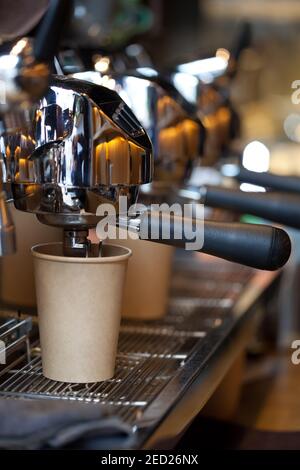 moderna macchina da caffè professionale in caffetteria con caffè che si versa in una tazza di carta da asporto, nessuno Foto Stock