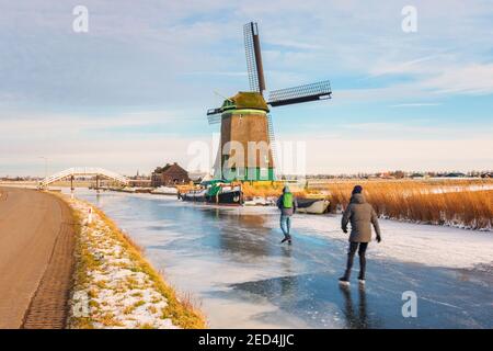 Due pattinatori di ghiaccio che pattinano su una furgonata fossa di polder a Opmeer, Paesi Bassi, in un freddo giorno di febbraio del 2021 Foto Stock