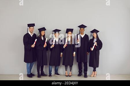 Gruppo di studenti sorridenti laureati multietnici in possesso di diplomi nelle mani Foto Stock