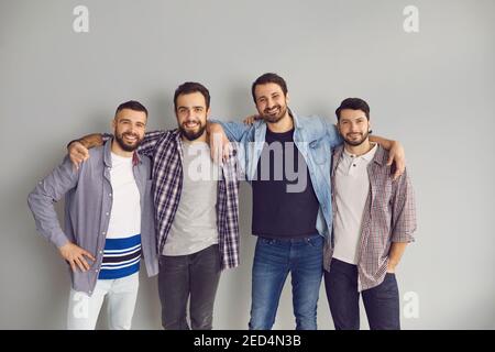 Ritratto di amici felici che si levano in piedi con le braccia intorno a loro spalle in studio Foto Stock