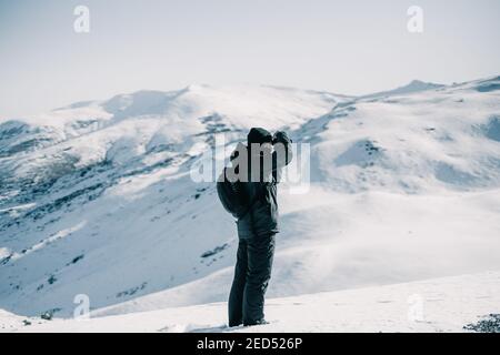 Fotografo di avventura che scatta una foto su una montagna innevata. Foto Stock