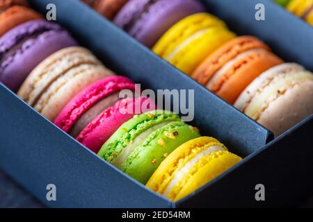 Vari macaroni colorati o macaroni francesi di fila in una scatola regalo, confezione a base di meringa dolce fatta con albume d'uovo, zucchero a velo, granulato Foto Stock