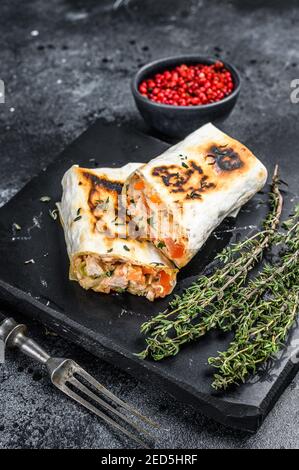 Donare il rotolo di kebab in una lavasca con pollo e carne di manzo. Sfondo di legno nero. Vista dall'alto Foto Stock