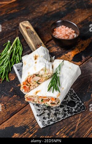 Sandwich Shawarma roll in una lavasca con pollo, manzo, funghi, formaggio. Sfondo di legno scuro. Vista dall'alto Foto Stock