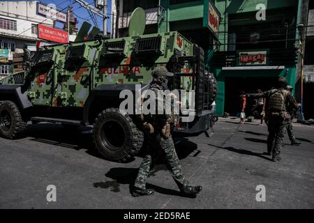 I membri della polizia nazionale filippina (PNP) pattugliano un mercato pubblico per verificare che sia mantenuta una distanza sociale sufficiente per rallentare la diffusione del coronavirus durante un blocco a Manila, Filippine. Foto Stock