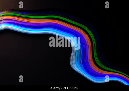 Onda astratta di colore arricciata carta strip arcobaleno su sfondo nero Foto Stock