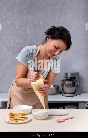 Lo chef versa la panna in una ciotola. Processo di fabbricazione della torta. Foto Stock