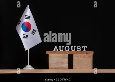 Calendario in legno di agosto con bandiera della Corea del Sud su sfondo nero. Date della Corea del Sud nel mese di agosto. Foto Stock
