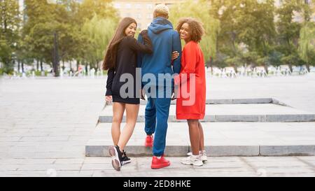 Amici multietnici all'aperto. Due donne innamorate di un ragazzo diverse persone di gruppo Afro american asian trascorrere il tempo insieme multirazziale maschile femmina studente parco a piedi all'aperto Foto Stock