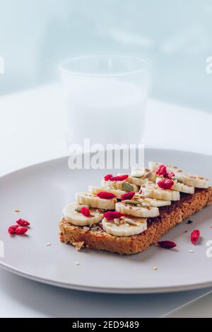 Colazione sana toast con burro di arachidi al cioccolato, banana, zucca, girasole e semi di lino, sesamo, bacche di goji. Spazio di copia Foto Stock