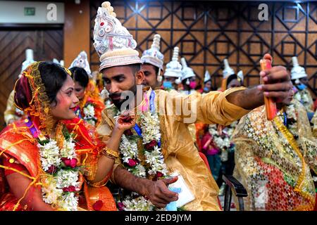 Una coppia prende un selfie durante la cerimonia del matrimonio di Messa. Una ONG chiamata 'Aloy phera' ha organizzato una cerimonia di matrimonio di massa di 70 coppie di diverse religioni a Kolkata il giorno di San Valentino per diffondere il messaggio di amore e di armonia sociale. A questo evento hanno partecipato coppie provenienti da varie comunità arretrate che non hanno un sostegno finanziario di base nella loro famiglia. Foto Stock