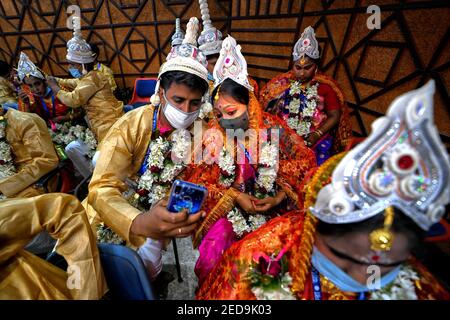 Una coppia prende un selfie durante la cerimonia del matrimonio di Messa. Una ONG chiamata 'Aloy phera' ha organizzato una cerimonia di matrimonio di massa di 70 coppie di diverse religioni a Kolkata il giorno di San Valentino per diffondere il messaggio di amore e di armonia sociale. A questo evento hanno partecipato coppie provenienti da varie comunità arretrate che non hanno un sostegno finanziario di base nella loro famiglia. Foto Stock