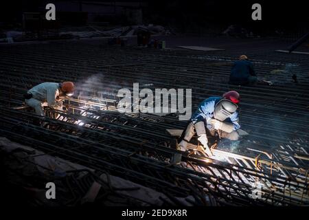 Un lavoratore che utilizza una torcia per saldatura fissa parti di una rete di acciaio per l'uso nella costruzione di un ponte alla periferia di Pechino, Cina, RPC. © Olli Geibel Foto Stock