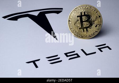 Bitcoin e il logo Tesla sono visualizzati su un documento cartaceo. Concetto di investimento nella criptovaluta. Messa a fuoco selettiva. Foto Stock