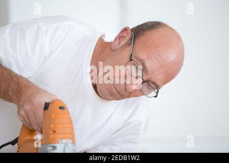 Un uomo con un elettrico seghetto alternativo per tagliare un asse di legno  Foto stock - Alamy