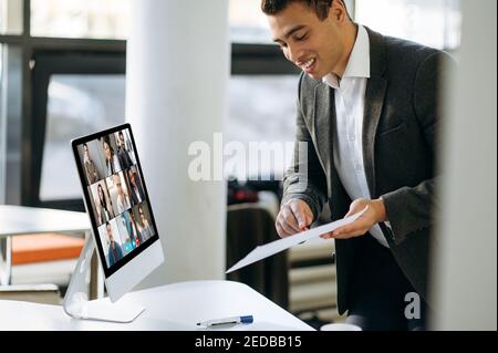 Il leader ispanico soddisfatto di affari comunica con i colleghi multirazziali riusciti di affari durante la video conferenza. Brainstorming, strategia, pianificazione Foto Stock