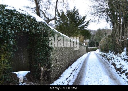 Una strada ghiacciata di campagna vicino a una bella vecchia parete di pietra a Magpie Bottom, Kent, vicino a Otford, Darent Valley, nel mese di febbraio neve Foto Stock