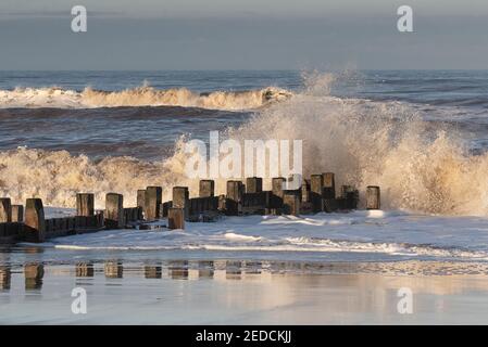 Luce solare invernale sulle onde infrangenti sulla costa nord del Norfolk, Regno Unito Foto Stock