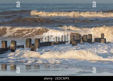 Luce solare invernale sulle onde infrangenti sulla costa nord del Norfolk, Regno Unito Foto Stock