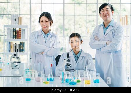 Ritratto di squadra di successo di medici asiatici maschili e femminili ricercatore e scienziato che lavora in laboratorio medico indossando camice da laboratorio cercando alla telecamera con braccia incrociate Foto Stock
