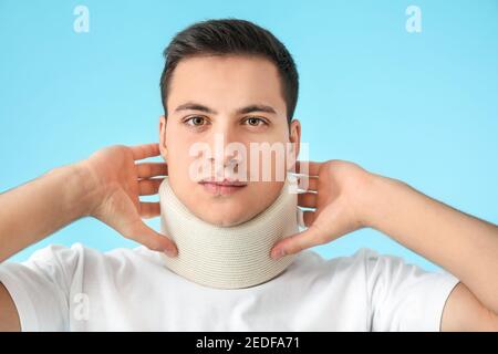 Giovane uomo con colletto cervicale sul collo su sfondo colorato Foto Stock