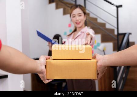 Mano di uomo di consegna che consegna il pacchetto al proprietario di abitazione. Donna che accetta una consegna di scatole dal liberyman. Mano di consegna l'uomo ha inviato il pacco di scatola a w Foto Stock