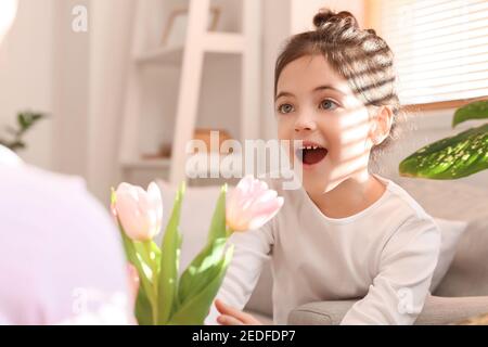 Sorprendo la bambina che riceve bouquet di fiori belli da lei madre a casa Foto Stock