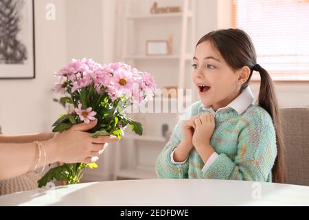 Sorprendo la bambina che riceve bouquet di fiori belli da lei madre a casa Foto Stock