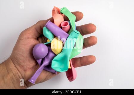 Palloncini colorati in una mano dell'uomo su uno sfondo bianco. Foto Stock