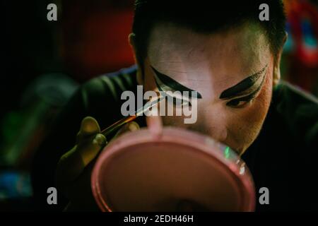 Un giocatore d'opera cinese sta mettendo sul suo backstage di trucco, preparandosi per lo spettacolo a Chinatown Bangkok. Foto Stock