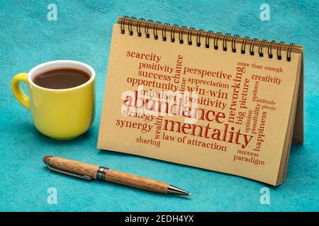 abbondanza mentalità parola nuvola in un notebook a spirale con una tazza di caffè, mentalità positiva e concetto win-win Foto Stock