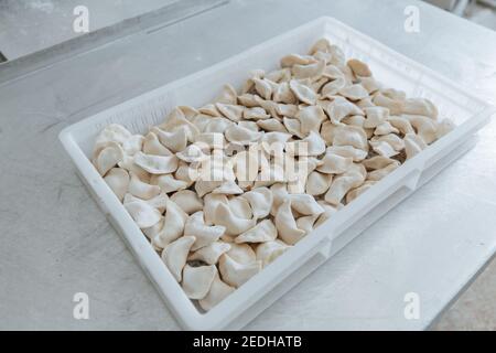 I gnocchi grezzi dell'impasto in farina fatta a mano si trovano in una scatola bianca. Foto Stock