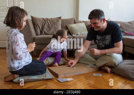 papà e bambini che giocano e imparano a giocare a carte home.stay a casa. week-end alla pandemia Foto Stock