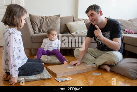 papà e bambini che giocano e imparano a giocare a carte home.stay a casa. week-end alla pandemia Foto Stock