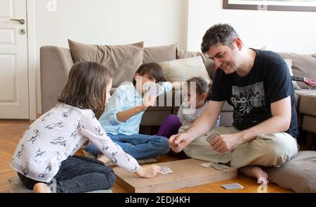 papà e bambini che giocano e imparano a giocare a carte home.stay a casa. week-end alla pandemia Foto Stock