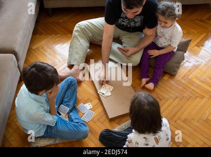 papà e bambini che giocano e imparano a giocare a carte home.stay a casa. week-end alla pandemia Foto Stock