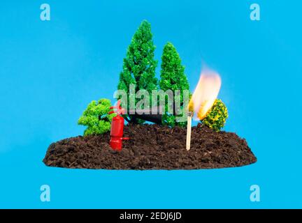 Set di foresta giocattolo in miniatura con un piccolo estintore accanto a una partita in fiamme. Concetto di prevenzione degli incendi boschivi. Foto Stock