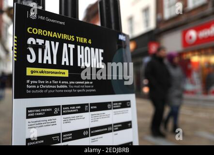 File foto datata 26/12/20 di persone che fanno la loro strada oltre un incoronavirus governo Tier 4 segno sulla High Street a Winchester, Hampshire. Un gruppo influente di parlamentari di tutte le parti ha invitato il governo a stabilire criteri chiari per l'abolizione delle restrizioni e a colmare le lacune nei suoi sistemi di sostegno. Data di emissione: Lunedì 15 febbraio 2021. Foto Stock