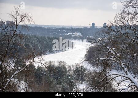 Fiume congelato Neris a Vilnius, Lituania, con la città e la foresta sullo sfondo, vista aerea Foto Stock