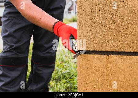 Adesivo a base di cemento per blocchi di pietra in muratura e mattoni in costruzione - un muratore professionale al lavoro Foto Stock