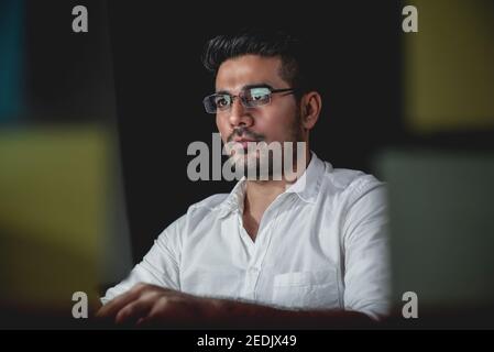 Bell'uomo d'affari asiatico che si concentra sul lavoro di notte con serio faccia Foto Stock