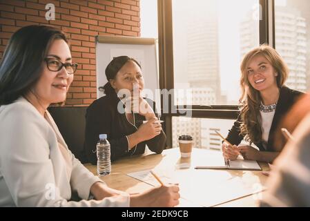 Gruppo di diverse leader imprenditrici che ascoltano la presentazione in riunione camera in ufficio Foto Stock