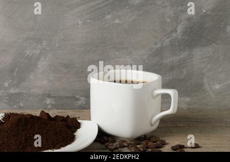 Una tazza di caffè con chicchi di caffè e caffè macinato su un piattino. Messa a fuoco selettiva. Foto Stock