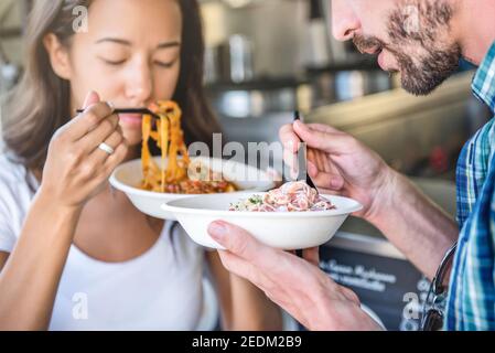 Coppia che tiene piatti da asporto di pasta al camion del cibo, mangiare con piacere Foto Stock