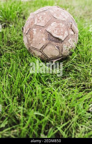 Vecchia palla da calcio in pelle vintage strappata su erba - storia del calcio Foto Stock