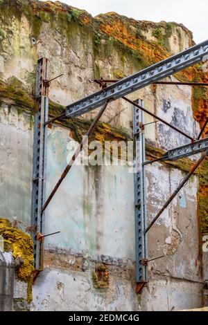 Travi di acciaio che sostengono una vecchia parete mussosa di un distrutto edificio Foto Stock