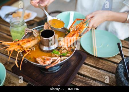 Donna che ha zuppa tailandese Tom Yum con gamberi e granchio in un ristorante Foto Stock