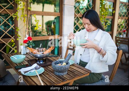 Donna asiatica che ha un pasto di cibo tailandese con tom zuppa di yum in un ristorante Foto Stock