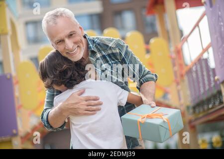 Felice padre che dà un regalo a suo figlio ed entrambi aspetto entusiasta Foto Stock